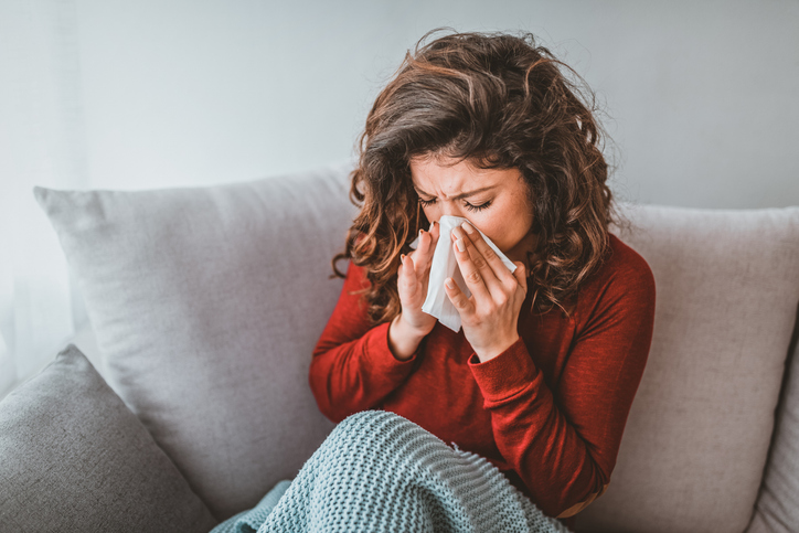 person unwell and coughing into tissue