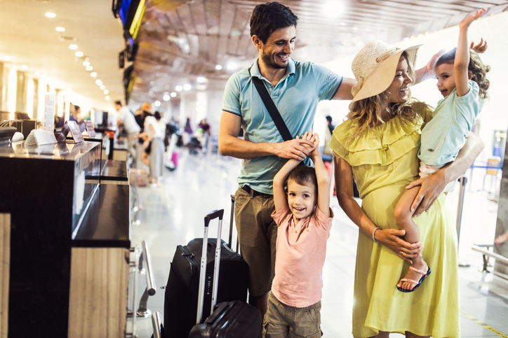 Young family at airport check-in desk with suitcase